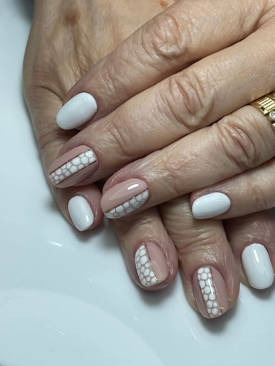 Manicura nude i blanca amb disseny de pell de rèptil i línia daurada